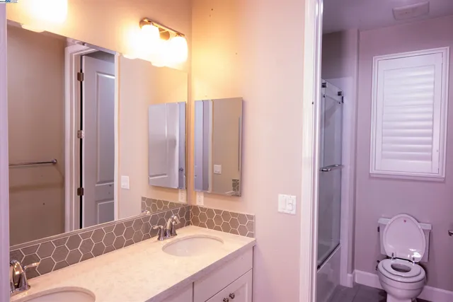 a bathroom with a granite countertop sink toilet a mirror and shower