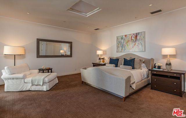 a bedroom with a bed flat screen tv and windows