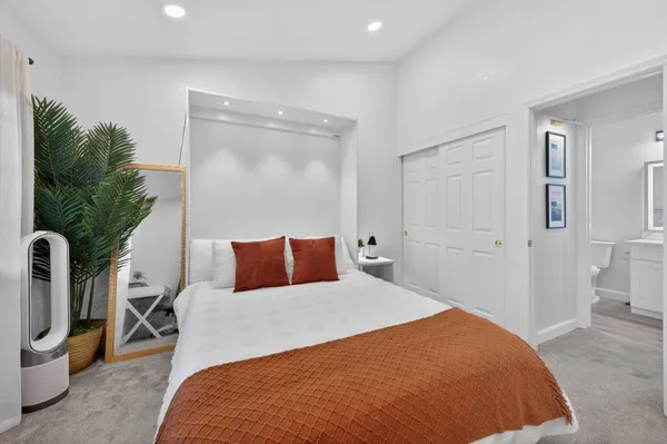 a bedroom with a large bed and a potted plant