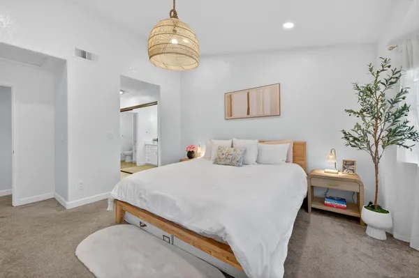a spacious bedroom with a bed and a chandelier