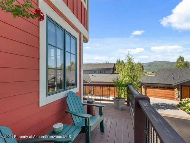 a balcony with couple of chairs and a potted plant