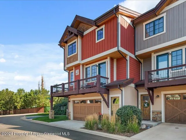 a view of a building with a small yard and large tree