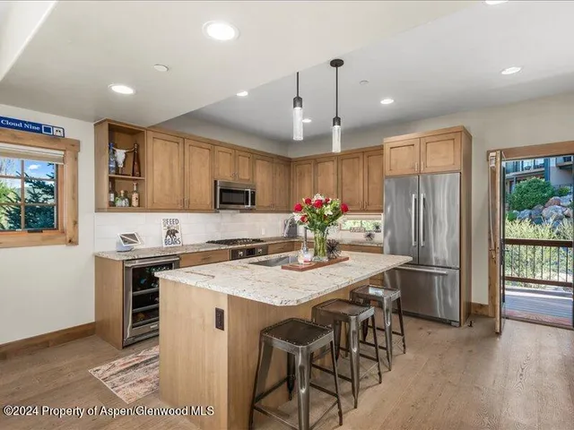 a kitchen with stainless steel appliances granite countertop a stove refrigerator a sink dishwasher a dining table and chairs with wooden floor