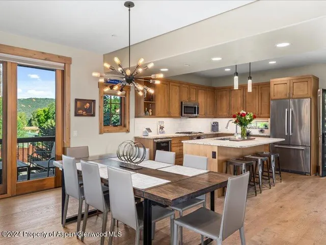 a kitchen with a dining table chairs stainless steel appliances and cabinets