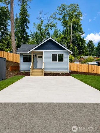 a front view of house with yard and trees in the background
