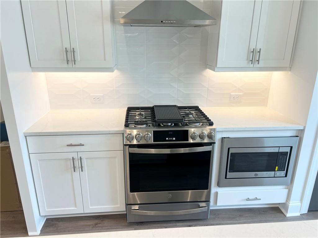 635 Silva Street, Unit 131 Cumming, GA 30040 - Photo 15 of 67 a kitchen with granite countertop white cabinets and stainless steel appliances