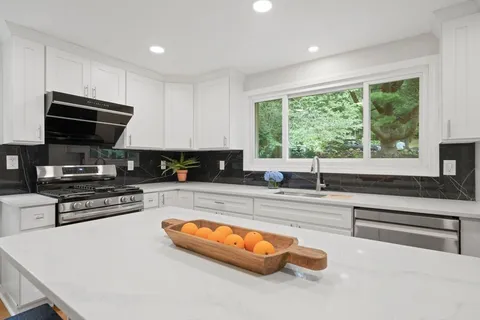 a kitchen with stainless steel appliances granite countertop a stove a sink and a microwave