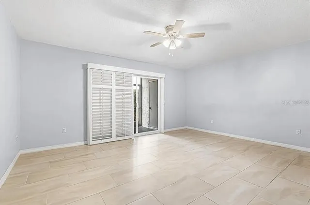 a view of an empty room with chandelier fan and fire place