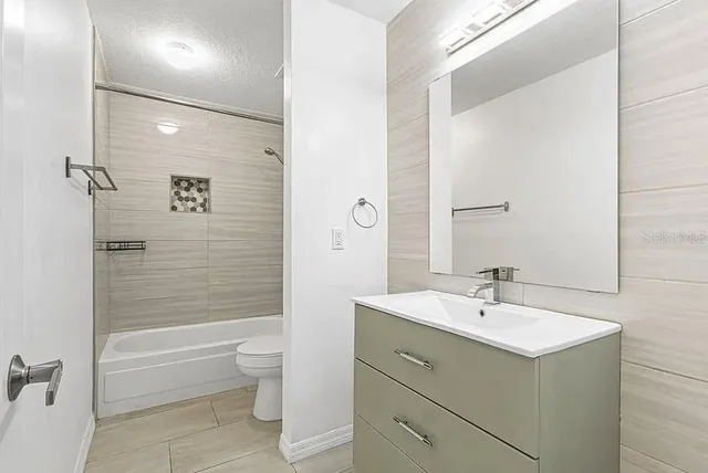 a bathroom with a bathtub shower sink vanity mirror and toilet