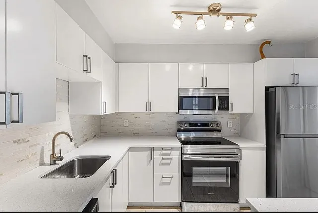 a kitchen with kitchen island a sink stainless steel appliances and cabinets
