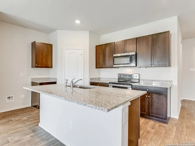 a kitchen with granite countertop a sink stove and microwave