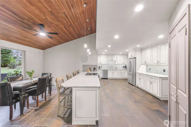 a large white kitchen with lots of counter space a sink appliances and a dining table