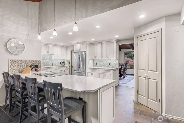 a kitchen with stainless steel appliances a table chairs refrigerator and cabinets
