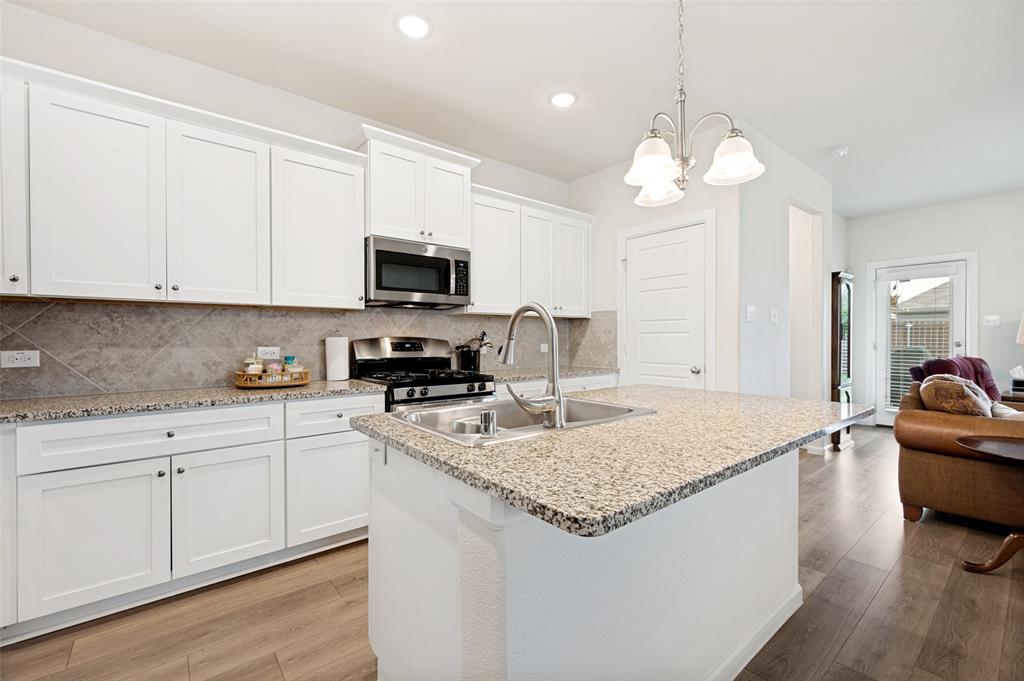 413 Wiggins Way Van Alstyne, TX 75495 - Photo 7 of 25 Kitchen featuring a central island with granite countertop, stainless steel double basin sink, and gooseneck faucet
