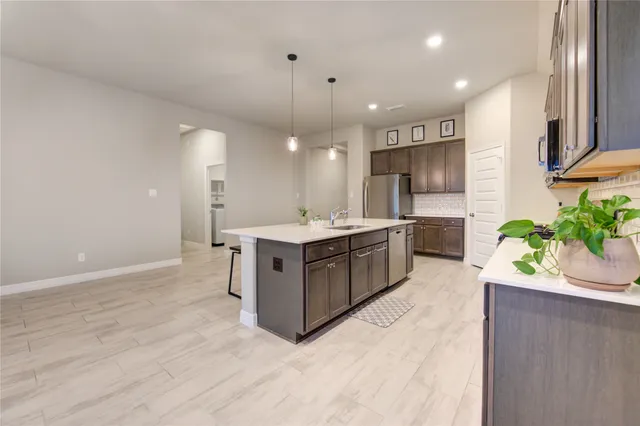 a large kitchen with a sink a counter top space stainless steel appliances and a window