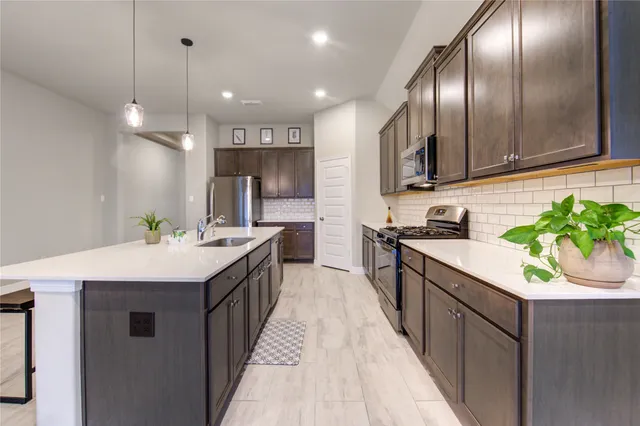 a kitchen with kitchen island granite countertop stainless steel appliances lots of counter space sink and a refrigerator