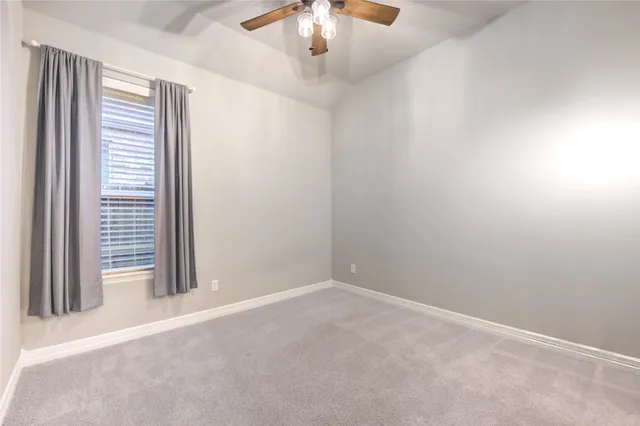 an empty room with a chandelier fan and windows