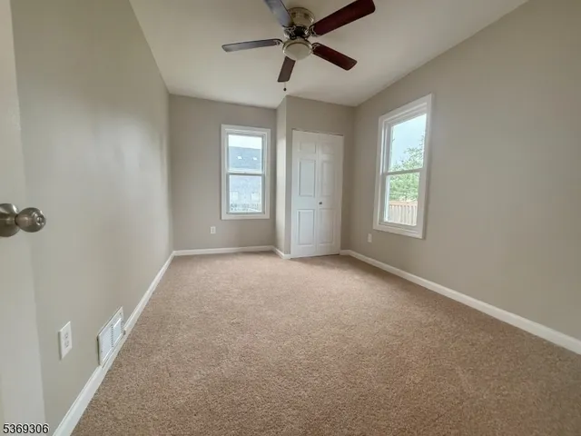 a view of a big room with windows and chandelier fan