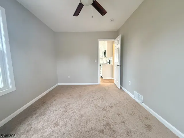 an empty room with ceiling fan and window