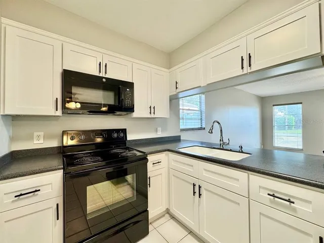 a kitchen with granite countertop white cabinets and black appliances