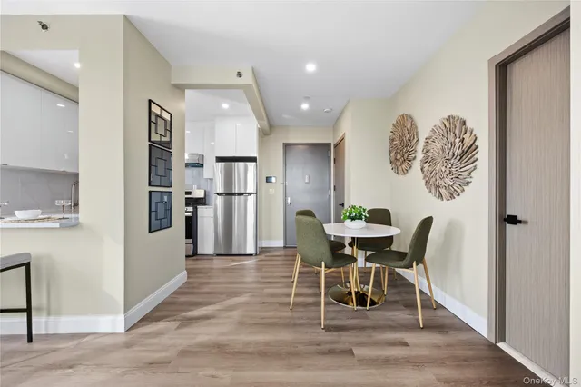 a dining room with stainless steel appliances wooden floor dining table and chairs