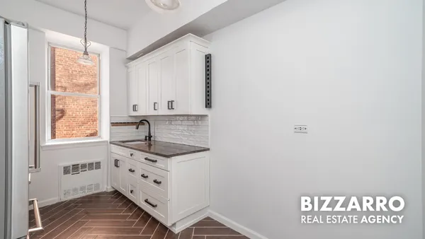 a kitchen with granite countertop white cabinets and window