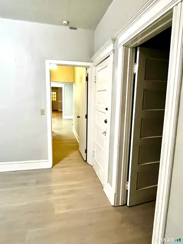 a view of a hallway with wooden floor and a bathroom