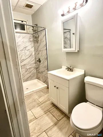 a bathroom with a sink a toilet a mirror and shower