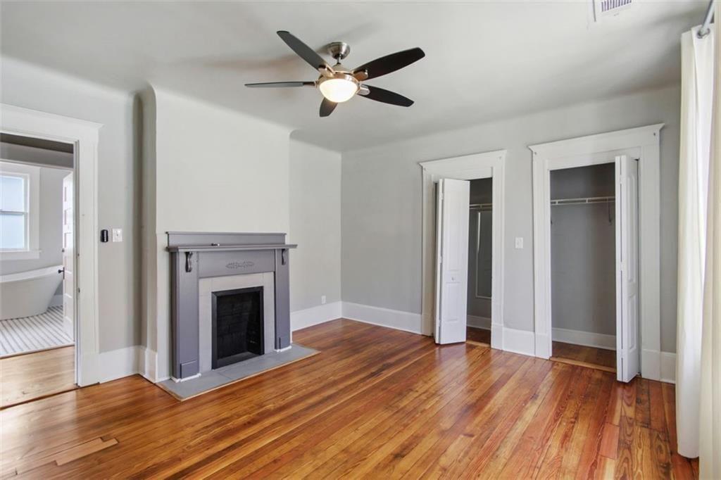 693 Myrtle Street Northeast Atlanta, GA 30308 - Photo 20 of 35 an empty room with wooden floor a ceiling fan and a fireplace