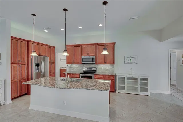 a large kitchen with kitchen island granite countertop a large counter top stainless steel appliances and a chandelier