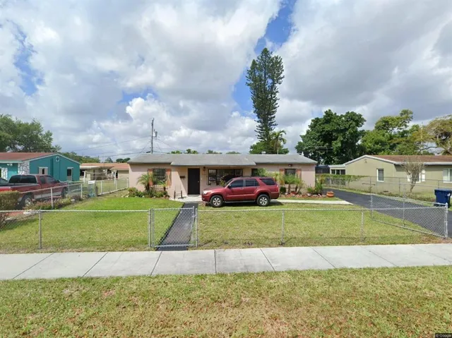 a front view of a house with a garden and trees