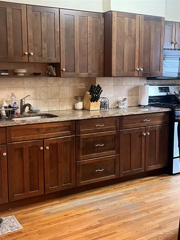 a kitchen with stainless steel appliances granite countertop a sink a stove and a cabinets