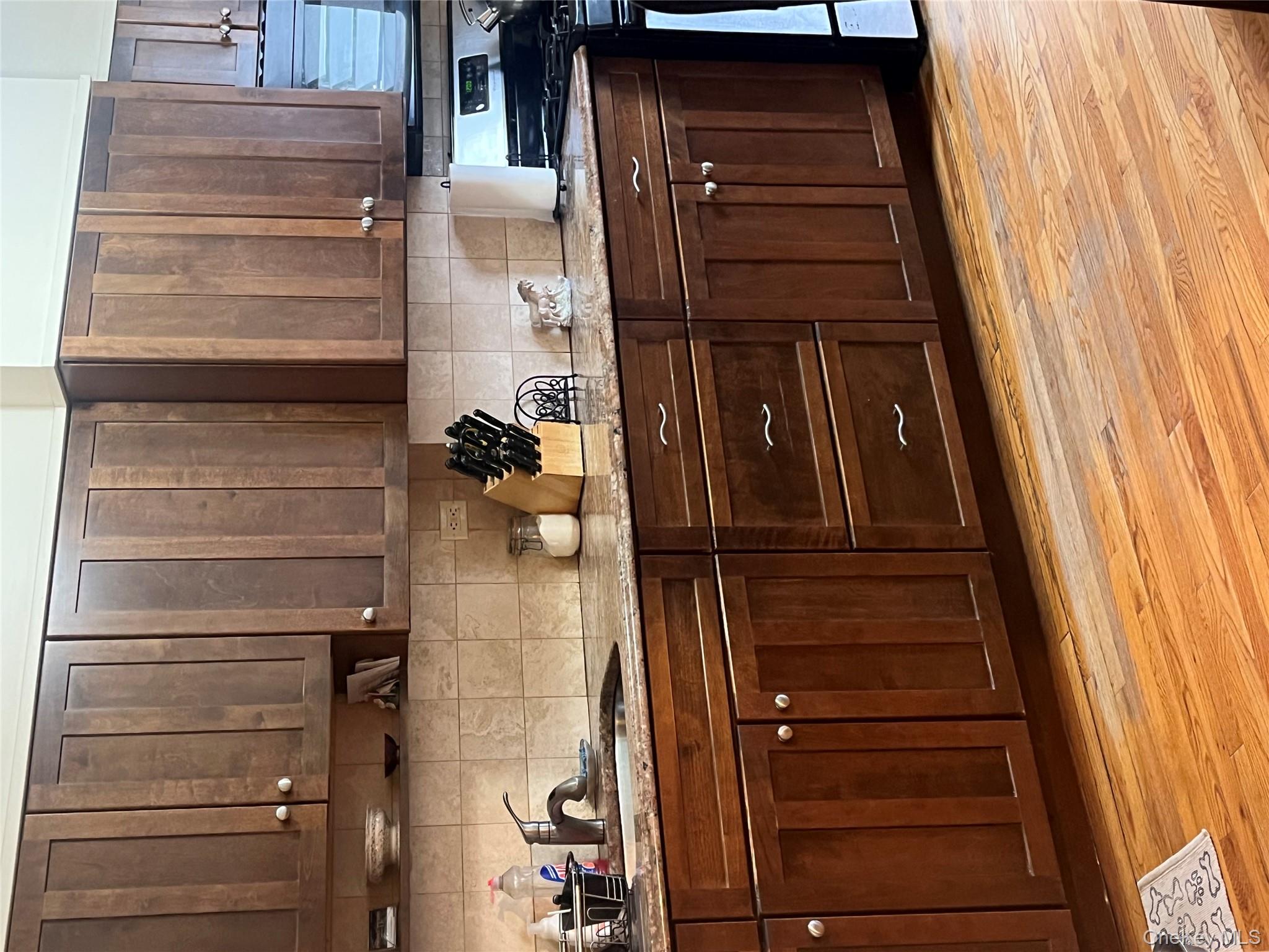 Kitchen with dark brown cabinetry, sink, light wood-type flooring, decorative backsplash, and stove