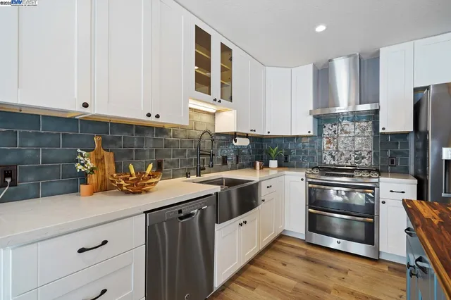 a kitchen with stainless steel appliances white cabinets and a stove top oven