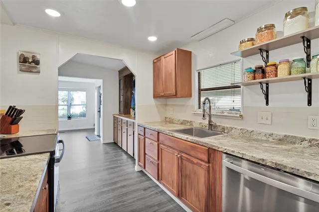 a kitchen with granite countertop a sink stove and cabinets