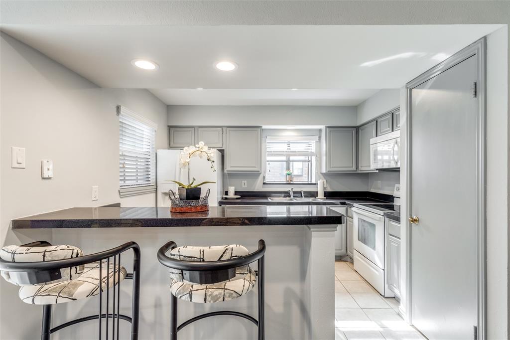 15221 Berry Trail, Unit 405 Dallas, TX 75248 - Photo 9 of 15 a kitchen with kitchen island granite countertop a sink and appliances