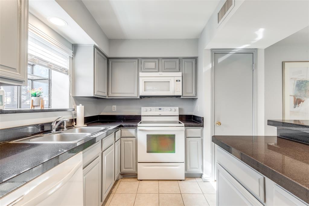 15221 Berry Trail, Unit 405 Dallas, TX 75248 - Photo 10 of 15 a kitchen with granite countertop white cabinets and white appliances