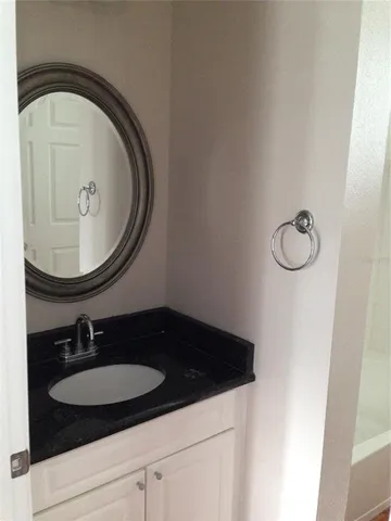 a bathroom with a granite countertop shower a mirror and a sink