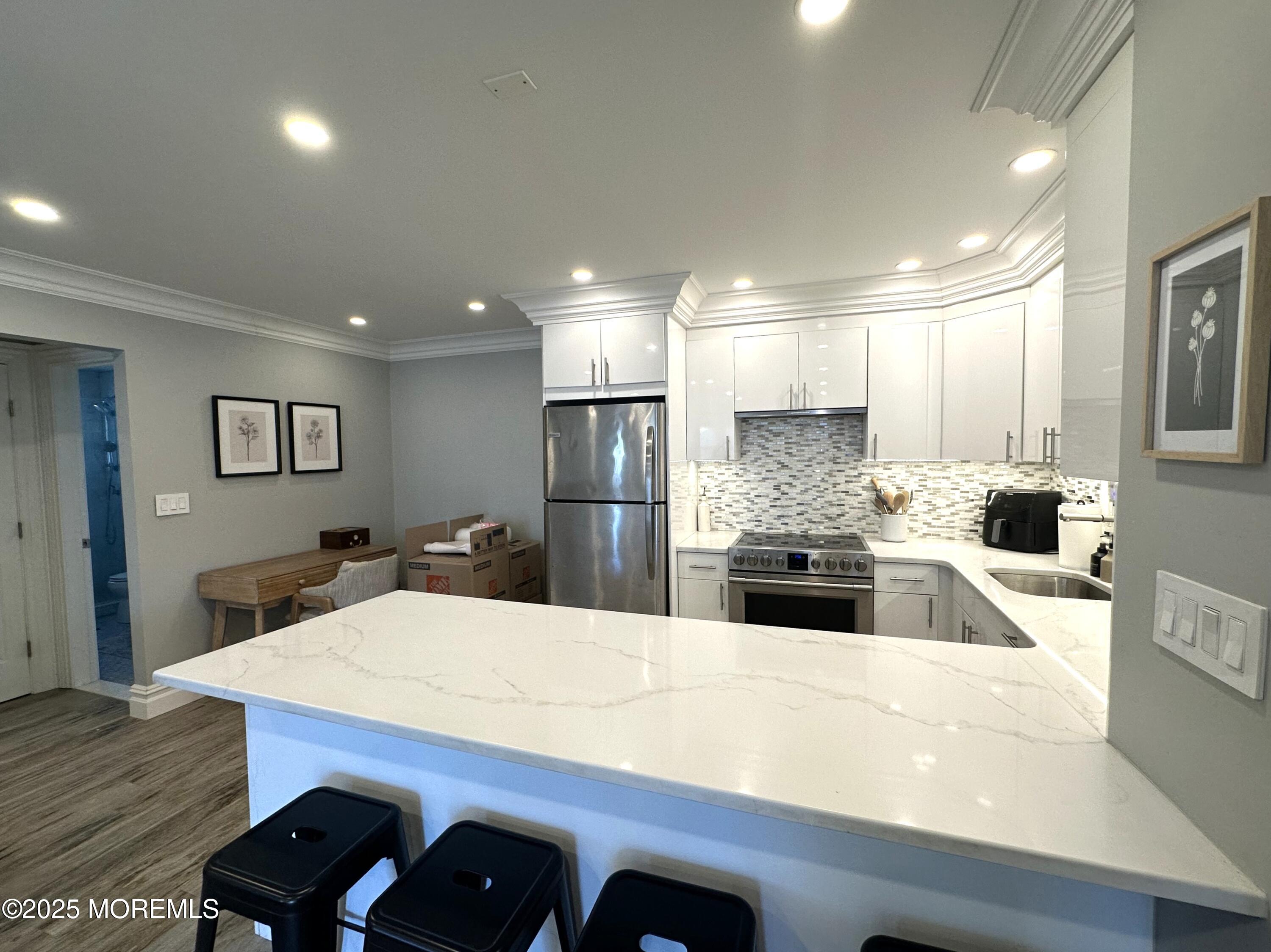 1501 Ocean Avenue, Unit A15 Belmar, NJ 07719 - Photo 6 of 17 a large kitchen with kitchen island a stove a sink a refrigerator and white cabinets with wooden floor