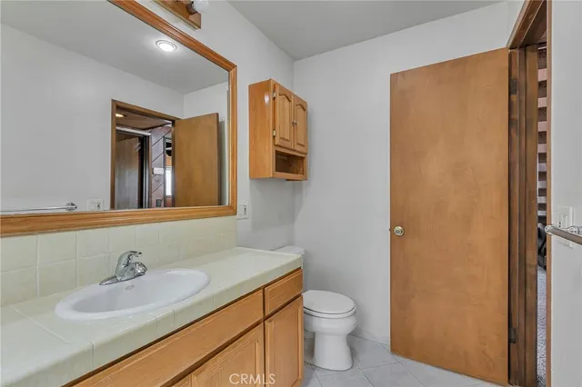 a bathroom with a granite countertop sink toilet and mirror