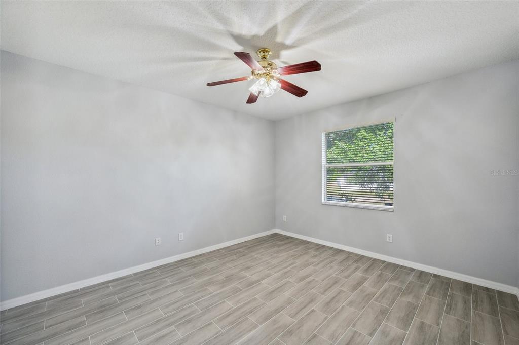 12351 Ridgedale Drive Hudson, FL 34669 - Photo 18 of 54 an empty room with wooden floor fan and windows