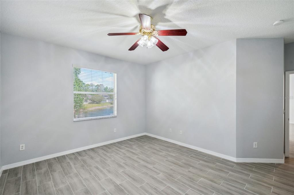 12351 Ridgedale Drive Hudson, FL 34669 - Photo 19 of 54 an empty room with wooden floor chandelier fan and windows