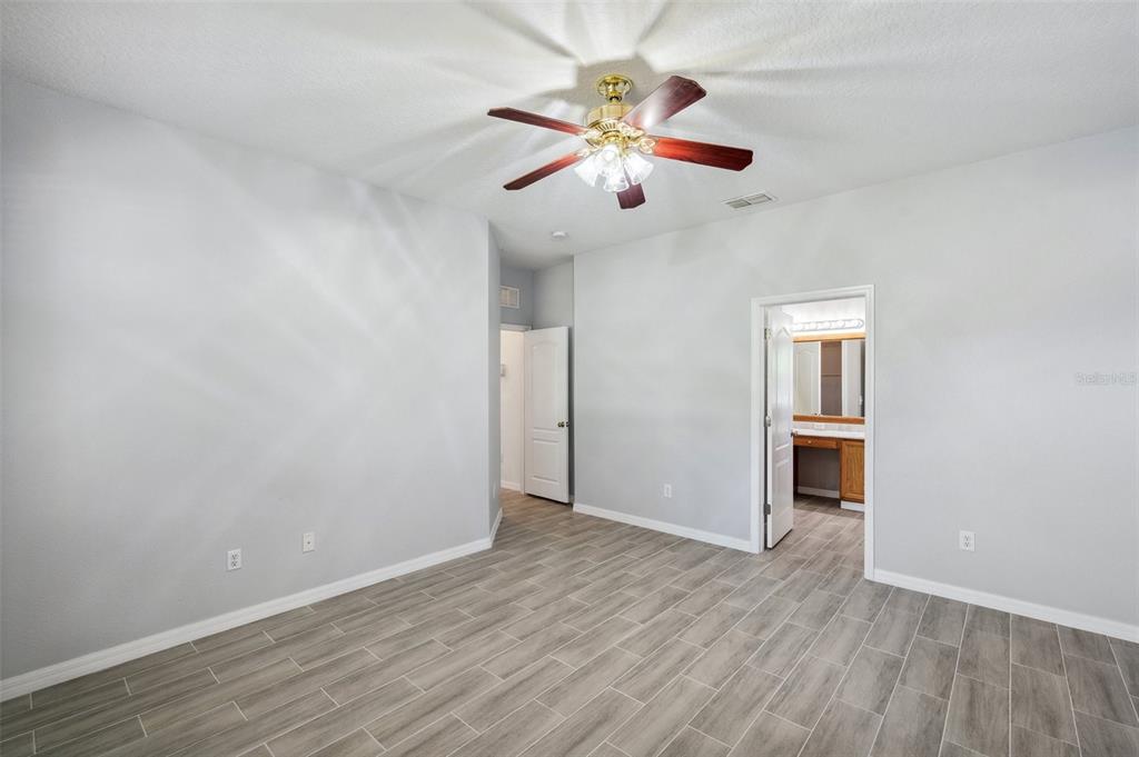 12351 Ridgedale Drive Hudson, FL 34669 - Photo 20 of 54 an empty room with wooden floor chandelier fan and windows