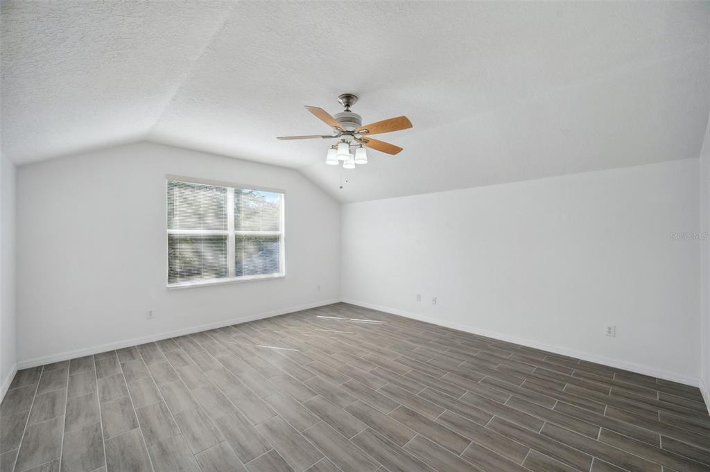 12351 Ridgedale Drive Hudson, FL 34669 - Photo 39 of 54 an empty room with wooden floor and ceiling fan