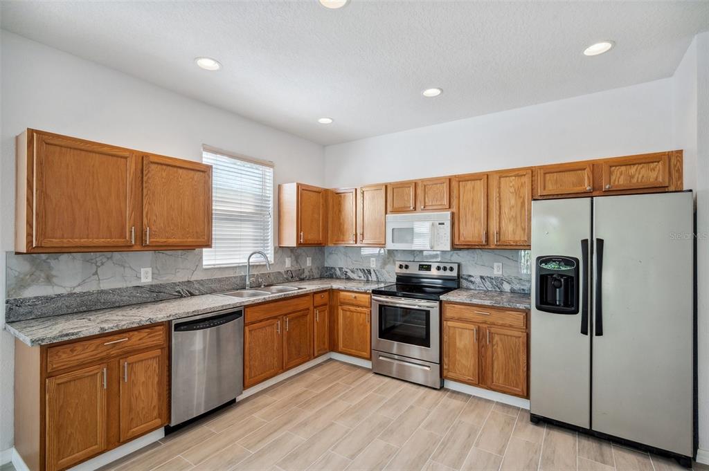 12351 Ridgedale Drive Hudson, FL 34669 - Photo 8 of 54 a kitchen with stainless steel appliances granite countertop wooden cabinets a sink a stove a refrigerator with grey cabinets and wooden floor