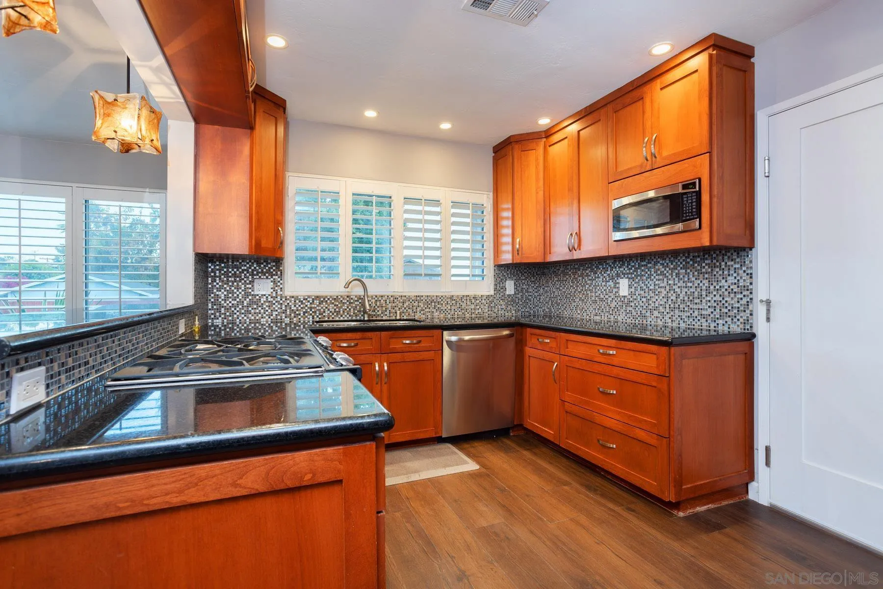 7354 Colony Road La Mesa, CA 91942 - Photo 12 of 24 a kitchen with stainless steel appliances granite countertop wooden cabinets a sink and a dishwasher next to a window