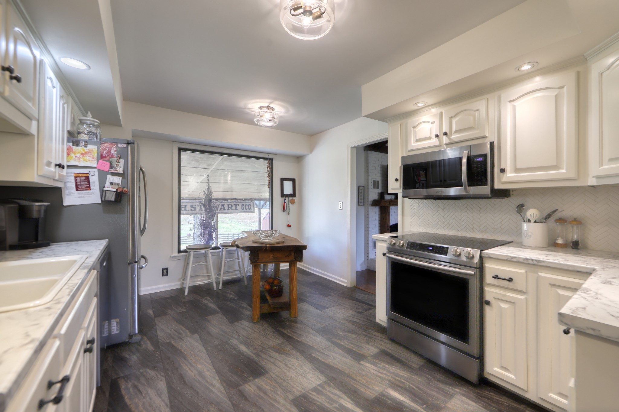 175 Bettis Road Lebanon, TN 37090 - Photo 11 of 49 a kitchen with stainless steel appliances a stove a sink dishwasher a microwave oven and a dining table with wooden floor