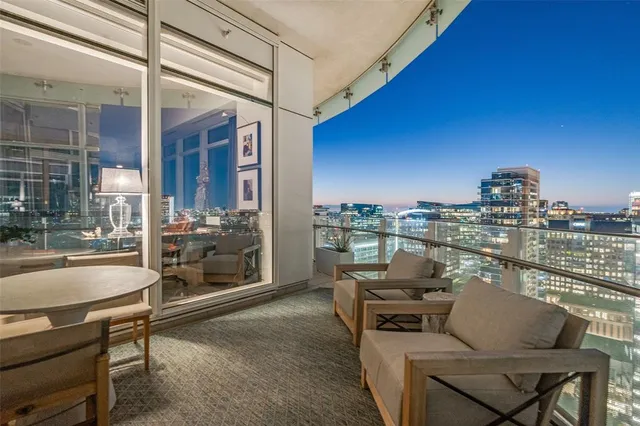 a living room with furniture large windows and wooden floor