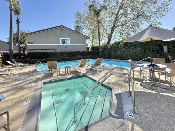 a view of a patio with couches table and chairs under an umbrella with a barbeque grill and plants