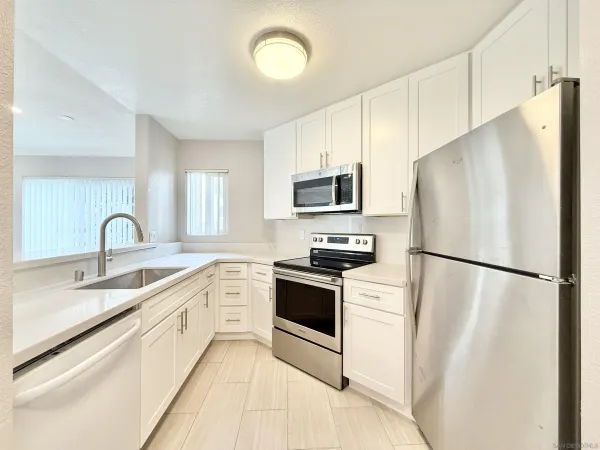 a white kitchen with stainless steel appliances a refrigerator sink and microwave
